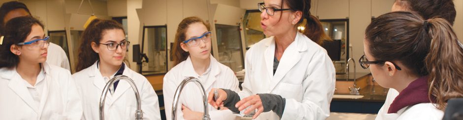 Enseignante donnant un cours dans un laboratoire entourée d'étudiant·es.