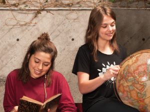 Deux étudiantes étudiant avec un livre et un globe terrestre représentant le programme des langues.