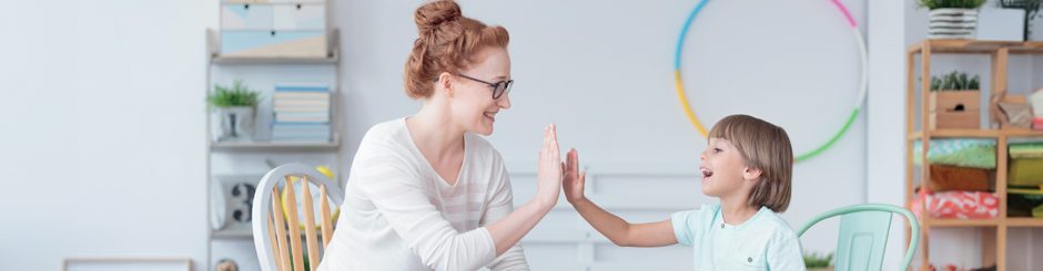 une femme et un enfant se tappant dans la main. Image représentant les sciences humaines, psychologie et interactions sociales.