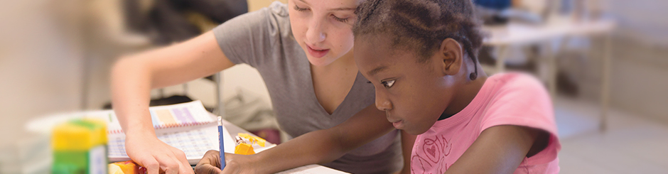 Une jeune tuteure aide une étudiante plus jeune à travailler sur ses devoirs.