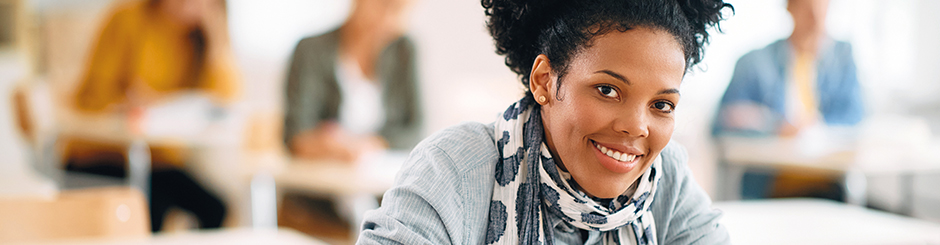 Femme très souriante dans une classe. Image représentant la formation continue.