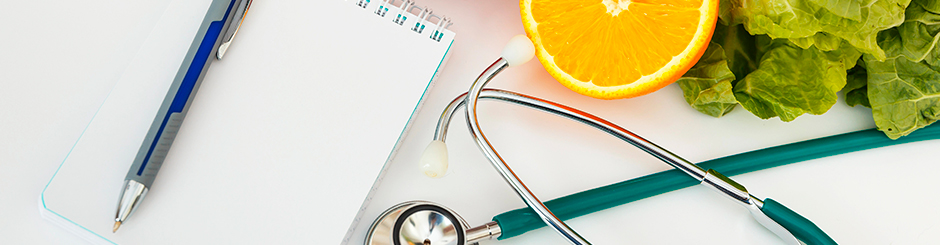 Image d'un stéthoscope, un cahier avec un crayon, une orange et de la laitue représentant la santé et l'alimentation.