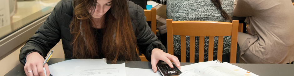 Jeune femme qui étudie et qui utilise une calculatrice.